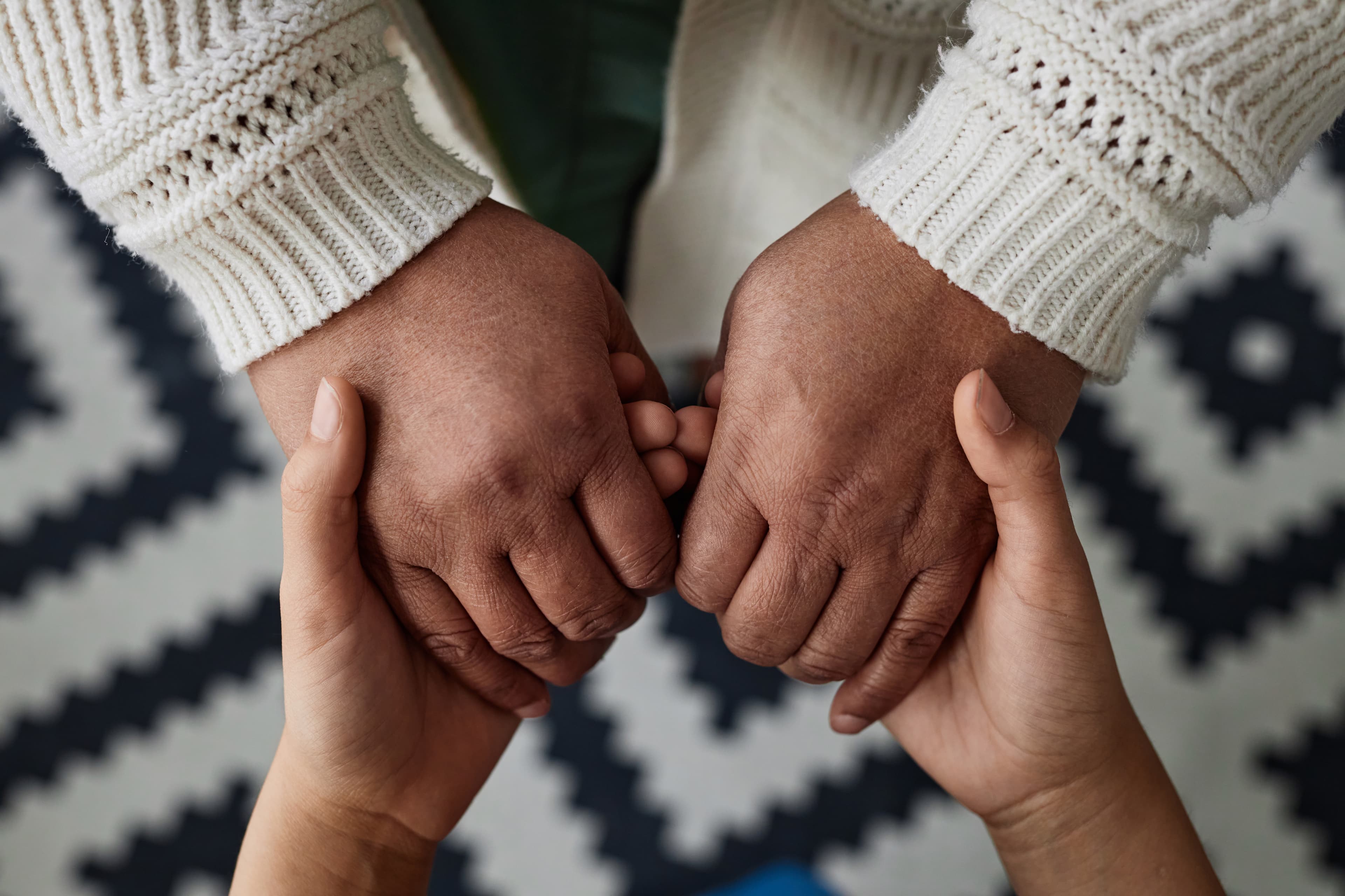 A clinician's and a patient's hands clasped in a moment of care
